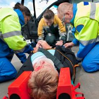 Paramedics and a fireman strapping a wounded woman with a neck brace on a stretcher