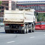 The collision of a truck and a car on a large city multi-lane road.