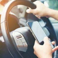 Driving while holding a mobile phone to work ,businessman ,vintage color tone Driving while holding a mobile phone to work ,businessman ,vintage color tone