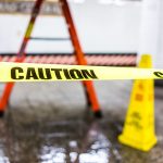 Caution tape sign in underground transit empty large platform in New York City NYC Subway Station in Grand Central, ladder, wet floor cone