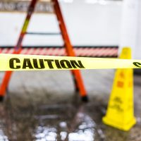 Caution tape sign in underground transit empty large platform in New York City NYC Subway Station in Grand Central, ladder, wet floor cone